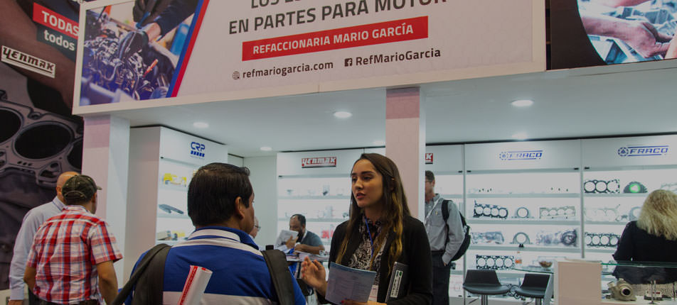 Ejecutiva de stand hablando con visitante en evento.